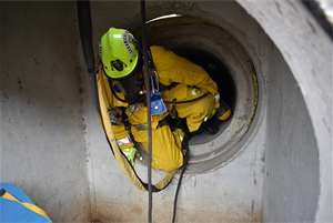 firefighter climbing out of simulation concrete drain pipe.
