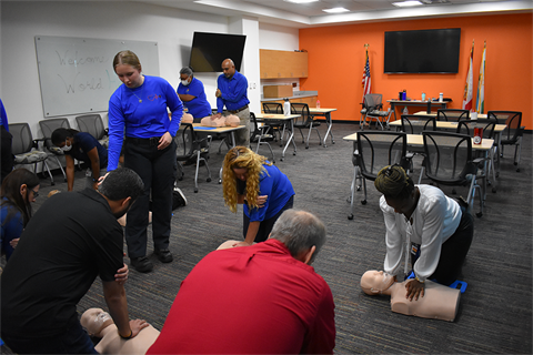 Instructor guiding a group of students through CPR training.