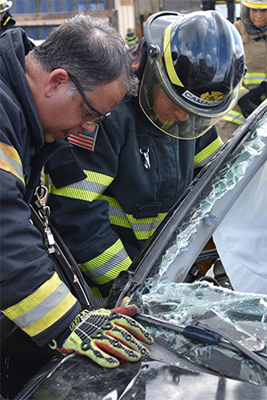 Fire instructor with student during vehicle extrication. 