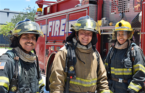 3 fire students smiling in gear. 